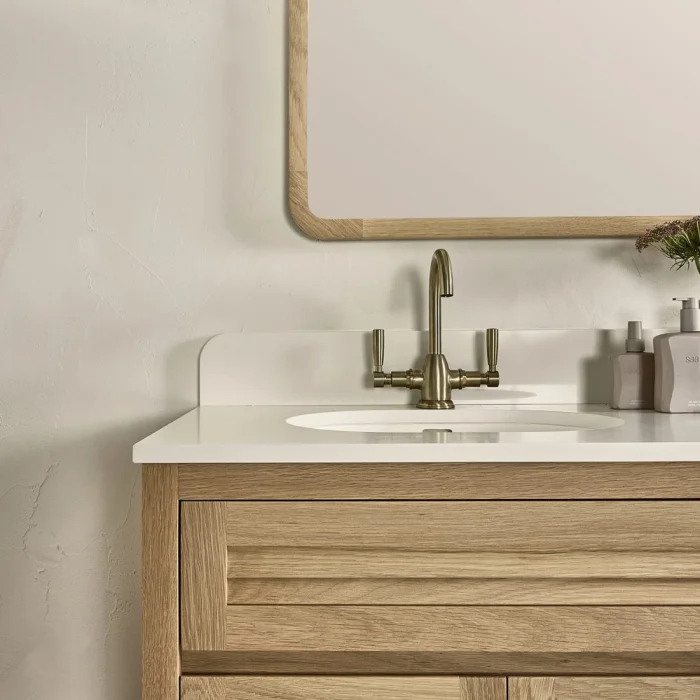 A bathroom vanity with a splashback underneath a curved timber frame mirror.