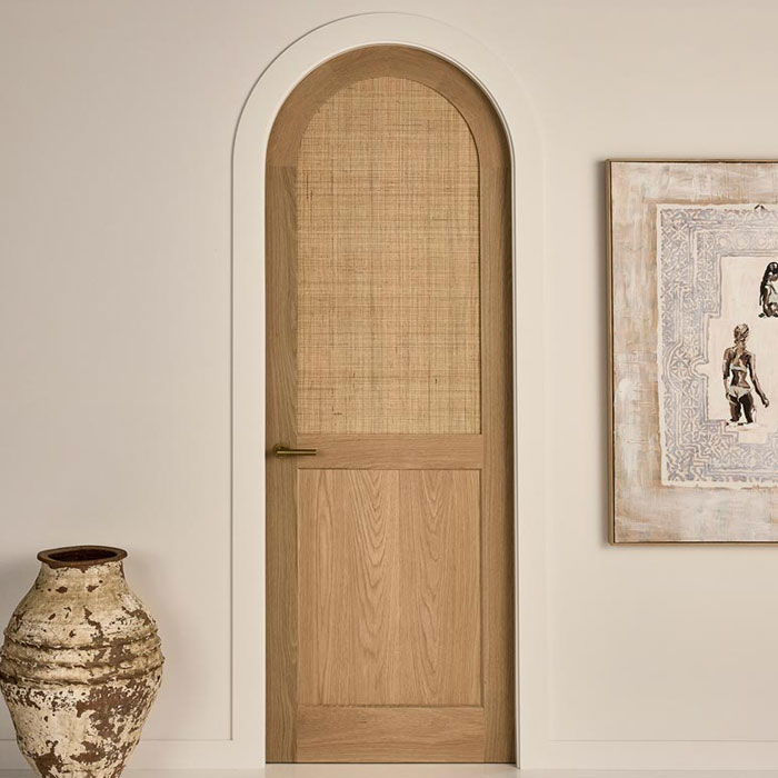 A rattan door in a curved frame showcasing the Arched Door Jamb & Architrave Set