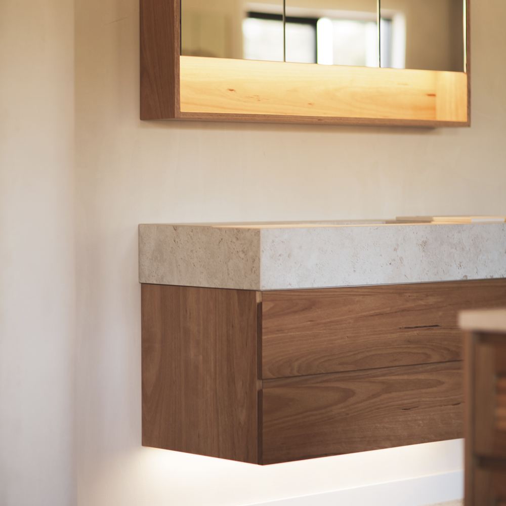LED lighting underneath a mirroed bathroom cabinet and above a timber bathroom vanity